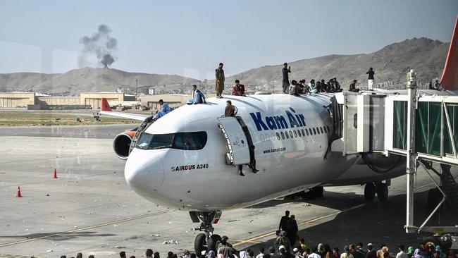 Afghan people climb atop a plane as they wait at the Kabul airport. Picture: AFP