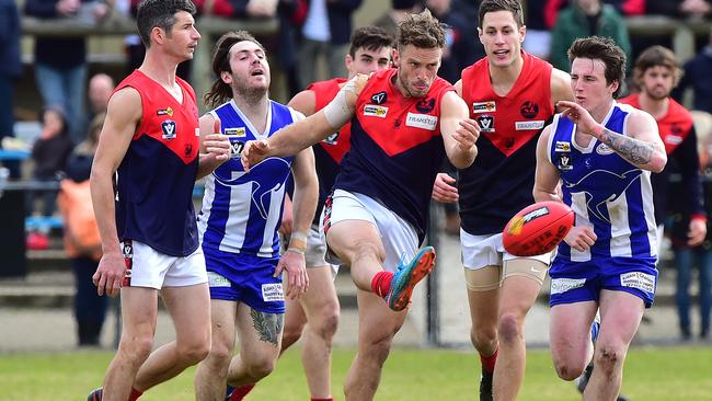 Pictured is Peninsula Football Netball League round 15 game of Australian Rules Football Langwarrin ( blue and white with blue shorts ) versus Mt Eliza ( red, white, blue with white shorts ) at Lloyd Park in Langwarrin. Rohan Heasley clears the ball from centre. Picture: Derrick den Hollander