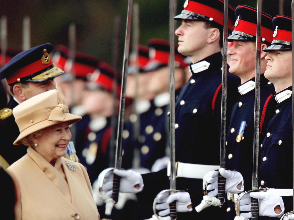 Prince Harry grinning while his grandmother inspects the Sovereign's Parade at the Royal Military Academy in Sandhurst in 2006. British royalty