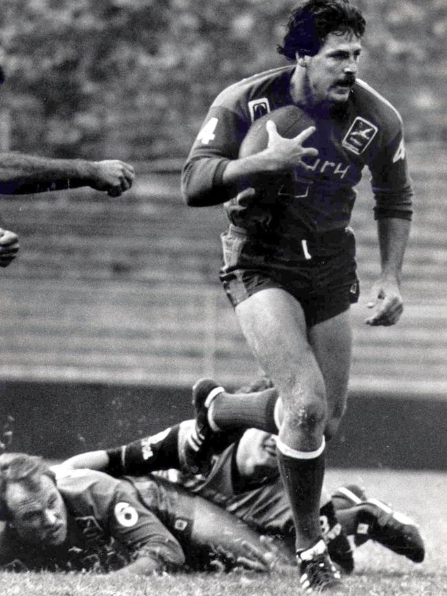 Wally Lewis on the ground watches teammate Gene Miles with the ball in 1984.