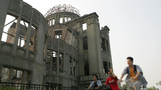 People ride the bicycles past the A-Bomb Dome in Hiroshima.