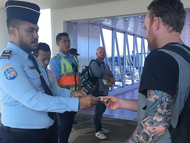 Mark Rossiter (right), is escorted onto the plane. Picture: Supplied