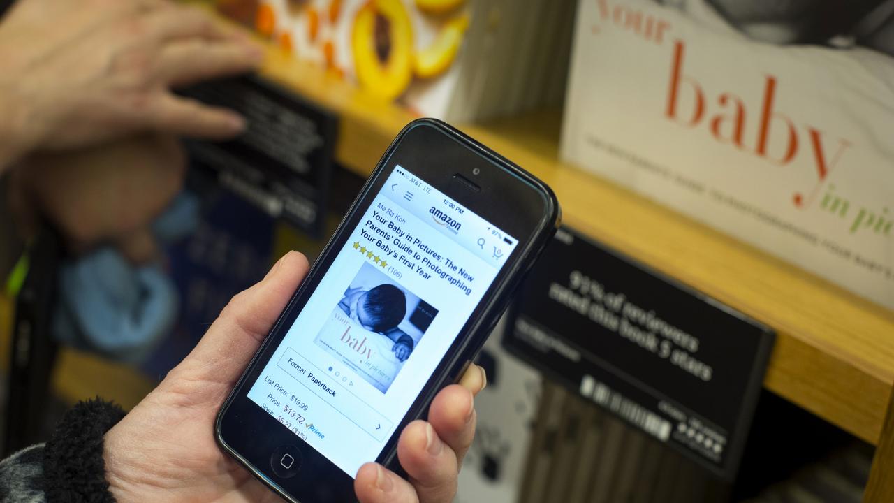 A customer checks the price of a book on Amazon.com using a mobile device at the Amazon Books store in Seattle, Washington Picture: David Ryder/Bloomberg