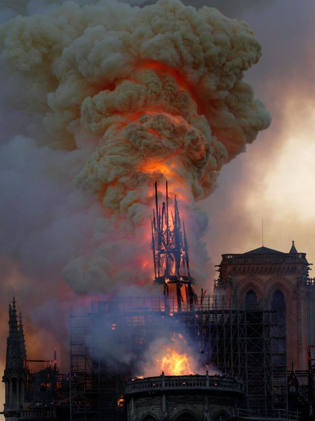 The steeple engulfed in flames collapses as the roof of the Notre-Dame de Paris Cathedral burns on April 15, 2019 in Paris. - A colossal fire swept through the famed Notre-Dame Cathedral in central Paris on April 15, 2019, causing a spire to collapse and raising fears over the future of the nearly millenium old building and its precious artworks. The fire, which began in the early evening, sent flames and huge clouds of grey smoke billowing into the Paris sky as stunned Parisians and tourists watched on in sheer horror. (Photo by Geoffroy VAN DER HASSELT / AFP)