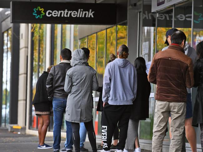 People queue up outside a Centrelink office in Melbourne on April 20, 2020, which delivers a range of government payments and services for retirees, the unemployed, families, carers and parents amongst others. - A report from the Grattan Institute predicts between 14 and 26 per cent of Australian workers could be out of work as a direct result of the coronavirus shutdown, and the crisis will have an enduring impact on jobs and the economy for years to come. (Photo by William WEST / AFP)