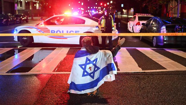 A man draped in the Israeli flag, bearing a cross and the name ‘Jesus’ at its centre, gestures as Metropolitan Police officers secure the area outside the Capital Jewish Museum following a shooting that left two people dead in Washington, DC on Thursday. Picture: AFP
