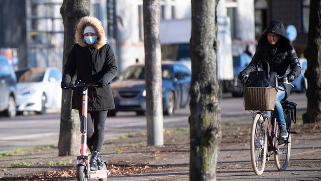 A woman wearing a face mask rides an electric scooter in Stockholm, Sweden. Picture: Fredrik Sandberg/AFP