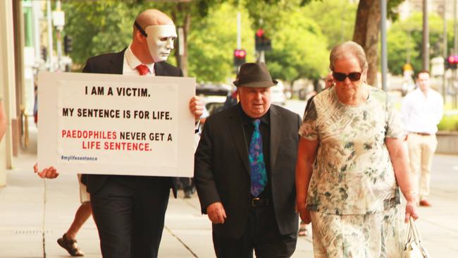 A victim confronts Vivian Deboo, centre, and his wife Margaret, right, outside court.