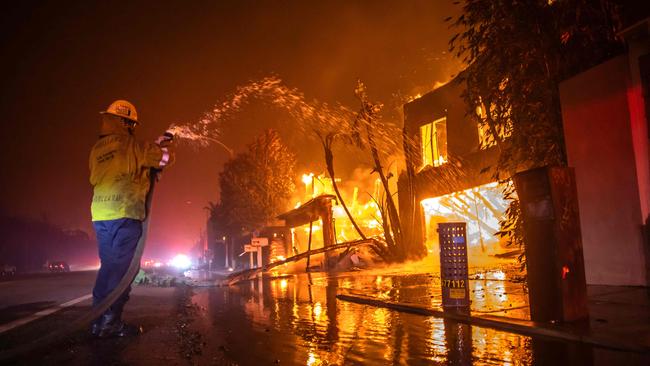 A firefighter battles the Palisades Fire while it burns homes at Pacific Coast Highway amid a powerful windstorm in Los Angeles. Picture: Getty