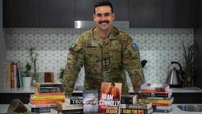 Australian Army Captain Dylan Conway, from the 6th Battalion, Royal Australian Regiment, with books he read while bedridden post-surgery.