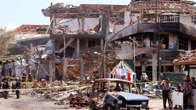 Forensic police officers and the wreckage of a car outside of the Sari Club nightclub in Kuta which was destroyed by a car bomb in 2002. Pic. AFP