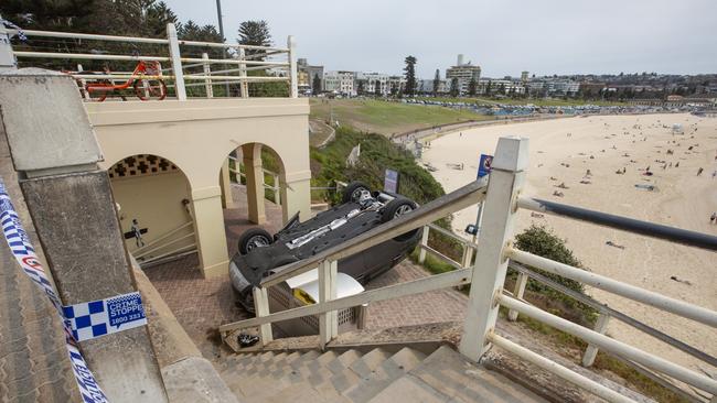 A car lies on its roof after crashing through a fence at Sydney’s Bondi Beach. Picture: OnScene