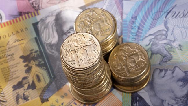 Three stacks of Australian one dollar coins on a background of bank notes. Shallow depth of field focus on tallest stack., cash money generic