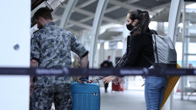 Arriving international passenger are helped on to buses at Sydney airport by ADF, police and airport security. Picture: Jane Dempster