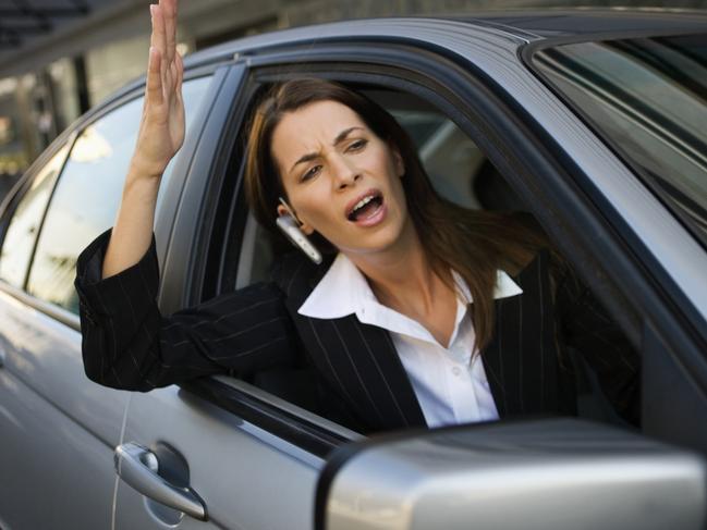 Businesswoman yelling out of car window. Road rage. Generic image.