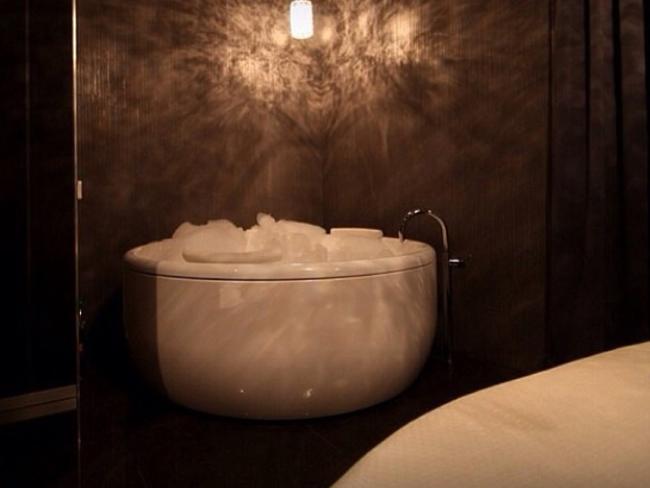 Images show a plush interior with dark walls, freestanding baths and round beds.