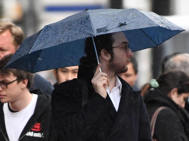 A man is seen waiting at the intersection of Elizabeth and Flinders street during an afternoon shower on Tuesday, July 17, 2017. Rain has been forecasted for the remainder of the week in Melbourne. (AAP Image/James Ross) NO ARCHIVING