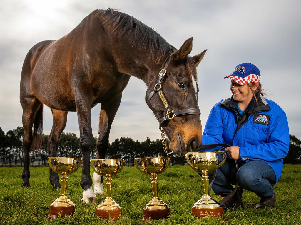 Three-time Melbourne Cup winner Makybe Diva pictured with her strapper Natalie Hinchcliffe, with her three Melbourne Cup trophies and the 2022 Lexus Melbourne Cup trophy. Picture: Mark Stewart