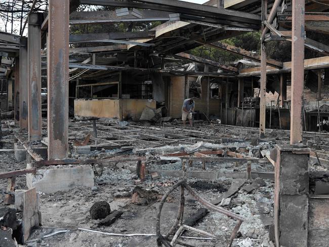 A man register damages at a bunt out cafe at the seaside resort of Mati, in the eastern Attica region after the deadly fires swept the area. Picture: AFP