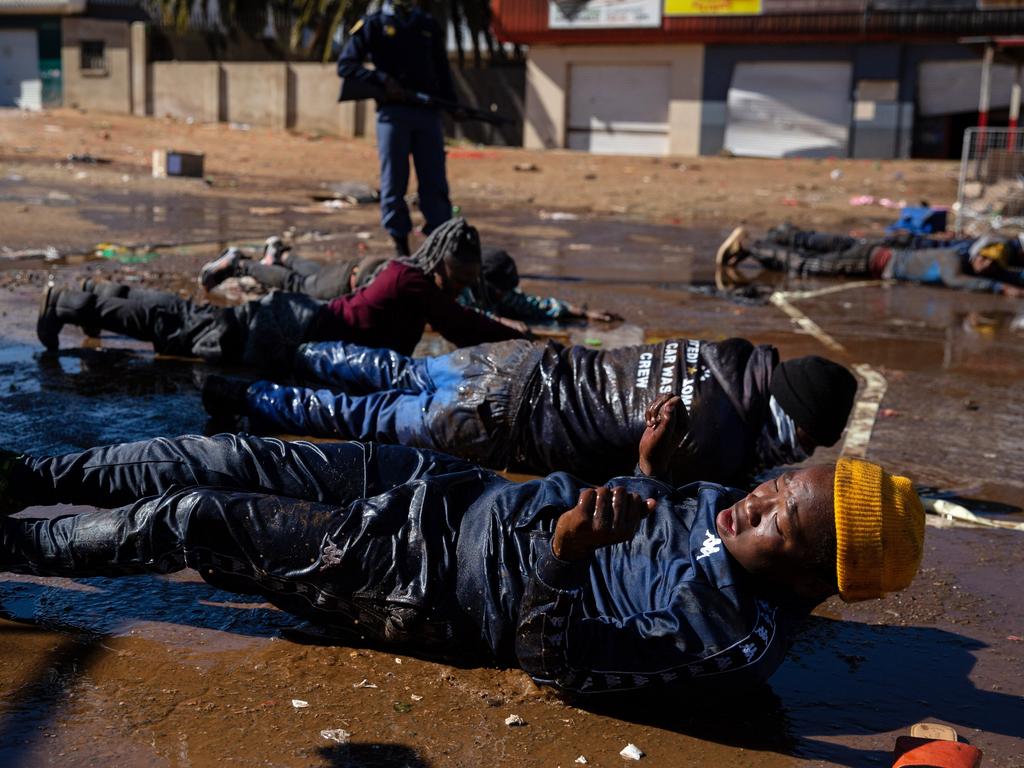 South African police make suspected looters lie down in muddy water after apprehending them in Soweto, Johannesburg. Picture: Getty Images