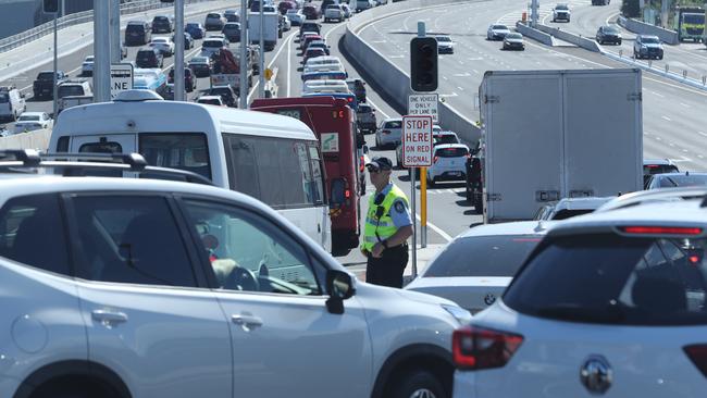 A policeman keeps an eye on commuter traffic feeding on to the Anzac Bridge on Victoria Rd, heading in to the city. Picture: Richard Dobson