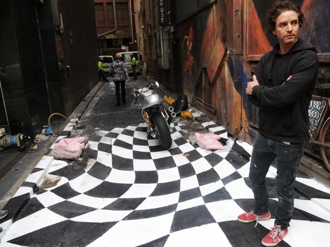 Fantauzzo attempts to protect his artwork from the clean up. Picture: Hamish Blair