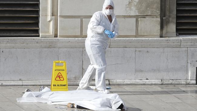 Investigative police officers work by a body under a white sheet outside Marseille's main train station. Picture: AP Photo/Claude Paris