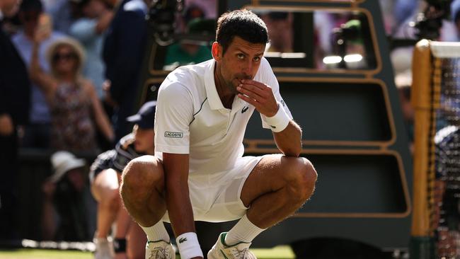 Novak Djokovic chows down on the rye-grass of the All-England Club. (Photo by Adrian DENNIS / AFP)