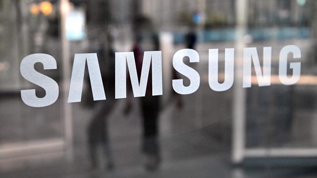 People walk past the Samsung logo displayed on a glass door at the company's Seocho building in Seoul. Photo: AFP