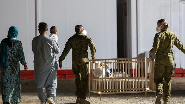 Signaller Charbal Nunes of 145 Signal Squadron and Corporal Nikkiska McGlashan, 3 Combat Signal Regiment help a family transport a cot to their room at the temporary camp for Afghan evacuees in the UAE. Picture: Supplied/Australian Department of Defence