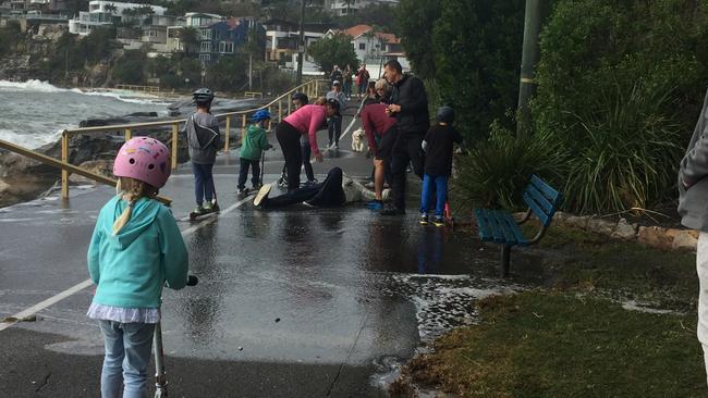 A man slips over on the footpath between Manly and Shelly Beach today. The path was severely damaged in the storm.