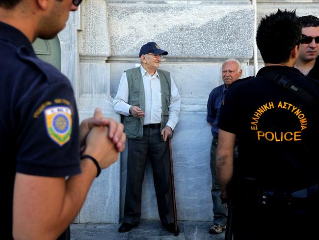 Tough times ... Pensioners chat to each other as police guard the headquarters of National Bank of Greece in Athens. Picture: AP/Spyros Tsakiris