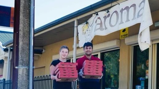 Two Aroma Pizza House employees, Jade and Benkil, with some of the food ordered during a prank and donated to Puddle Jumpers.