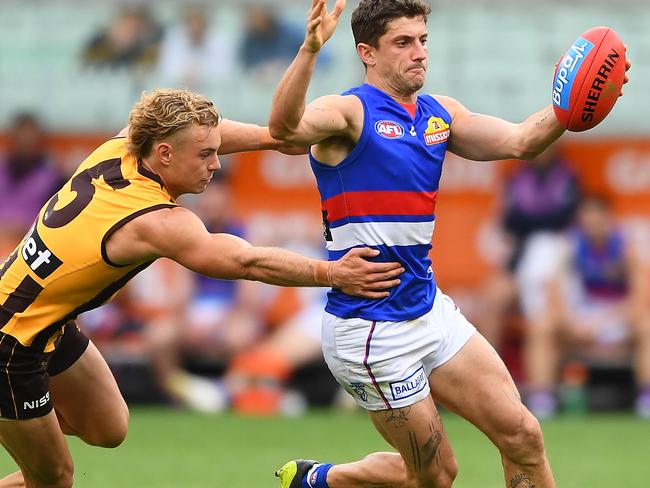 MELBOURNE, AUSTRALIA - MARCH 31: Tom Liberatore of the Bulldogs kicks whilst being tackled by James Worpel of the Hawks during the round two AFL match between the Hawthorn hawks and the Western Bulldogs at Melbourne Cricket Ground on March 31, 2019 in Melbourne, Australia. (Photo by Quinn Rooney/Getty Images)