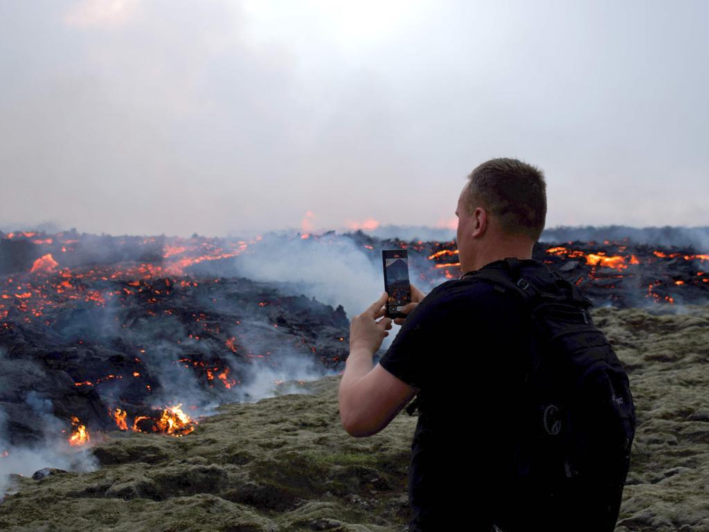 This picture taken on July 10, 2023 shows a man taking a picture of flowing lava during an volcanic eruption at Litli HrutuPicture: Jeremie RICHARD / AFP