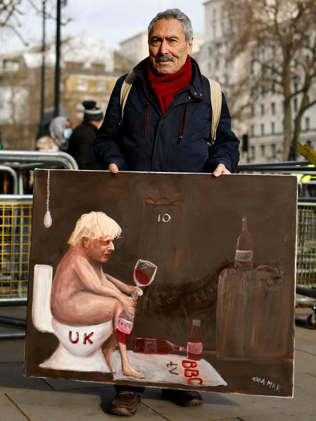 Political satiristt Kaya Mar stands outside the entrance to 10 Downing Street with a painting of Boris Johnson sitting on a toilet drinking wine. Picture: AFP