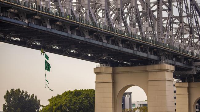 An activist dangles from the Story Bridge in a hammock as part of protests in Brisbane yesterday. Picture: AAP Image/Glenn Hunt