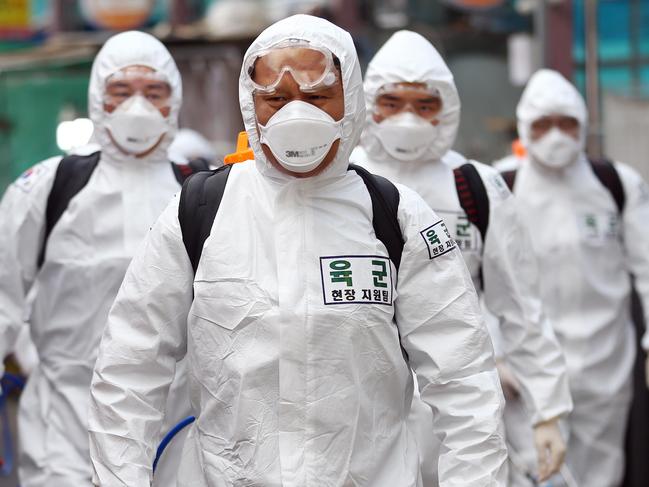 TOPSHOT - South Korean soldiers wearing protective gear spray disinfectant as part of preventive measures against the spread of the COVID-19 coronavirus, at a market in Daegu on March 2, 2020. - South Korea reported nearly 500 new coronavirus cases on March 2, sending the largest national total in the world outside China past 4,000. (Photo by - / YONHAP / AFP) / - South Korea OUT / REPUBLIC OF KOREA OUT  NO ARCHIVES  RESTRICTED TO SUBSCRIPTION USE