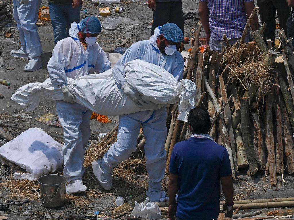 “Beyond crisis point”: Family members wearing PPE carry the body at a cremation ground in New Delhi. Picture: AFP