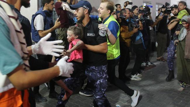 A member of the Palestinian security forces carries a wounded child into Al-Shifa hospital in Gaza City during retaliatory airstrikes on the Palestinian territory on October 11.