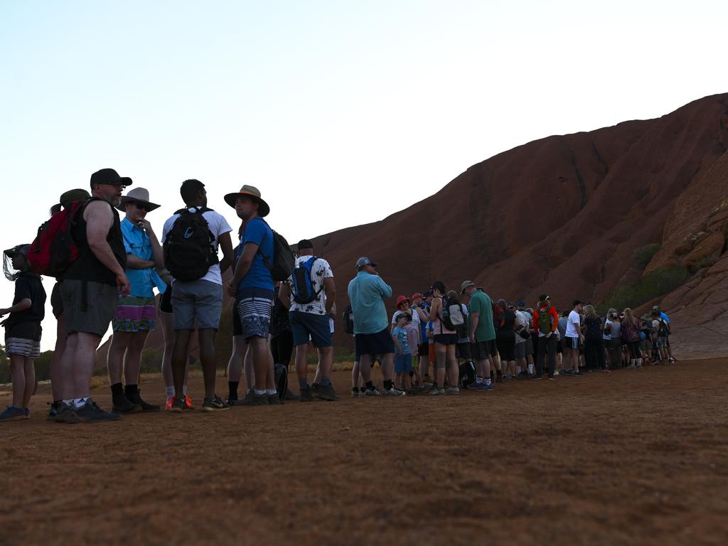 Tourists are seen lining up to climb Uluru ahead of a ban that takes effect on Saturday. Picture: AAP Image/Lukas Coch