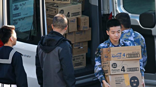 Chinese personnel load boxes of baby milk on to a warship. Picture: Adam Yip