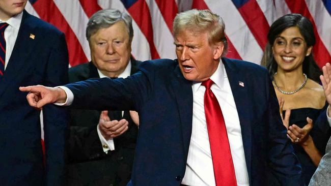 TOPSHOT - Former US President and Republican presidential candidate Donald Trump gestures at supporters after speaking as he holds hands with former US First Lady Melania Trump during an election night event at the West Palm Beach Convention Center in West Palm Beach, Florida, early on November 6, 2024. Republican former president Donald Trump closed in on a new term in the White House early November 6, 2024, just needing a handful of electoral votes to defeat Democratic Vice President Kamala Harris. (Photo by Jim WATSON / AFP)