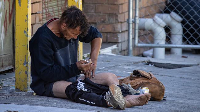 A man openly injects drugs into his leg only a few hundred metres from the safe injecting room. Picture: Jason Edwards