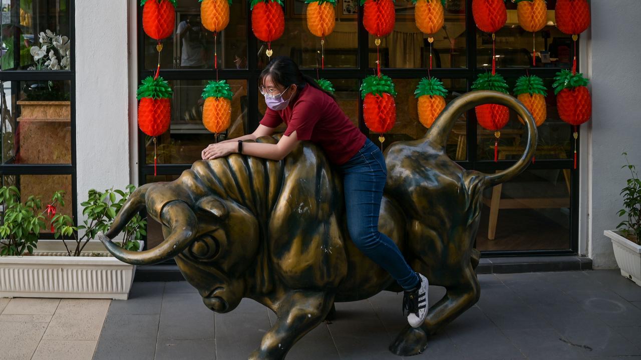 A woman sits on a bull statue before Lunar New Year outside a shop in Cyberjaya, Malaysia. Picture: AFP