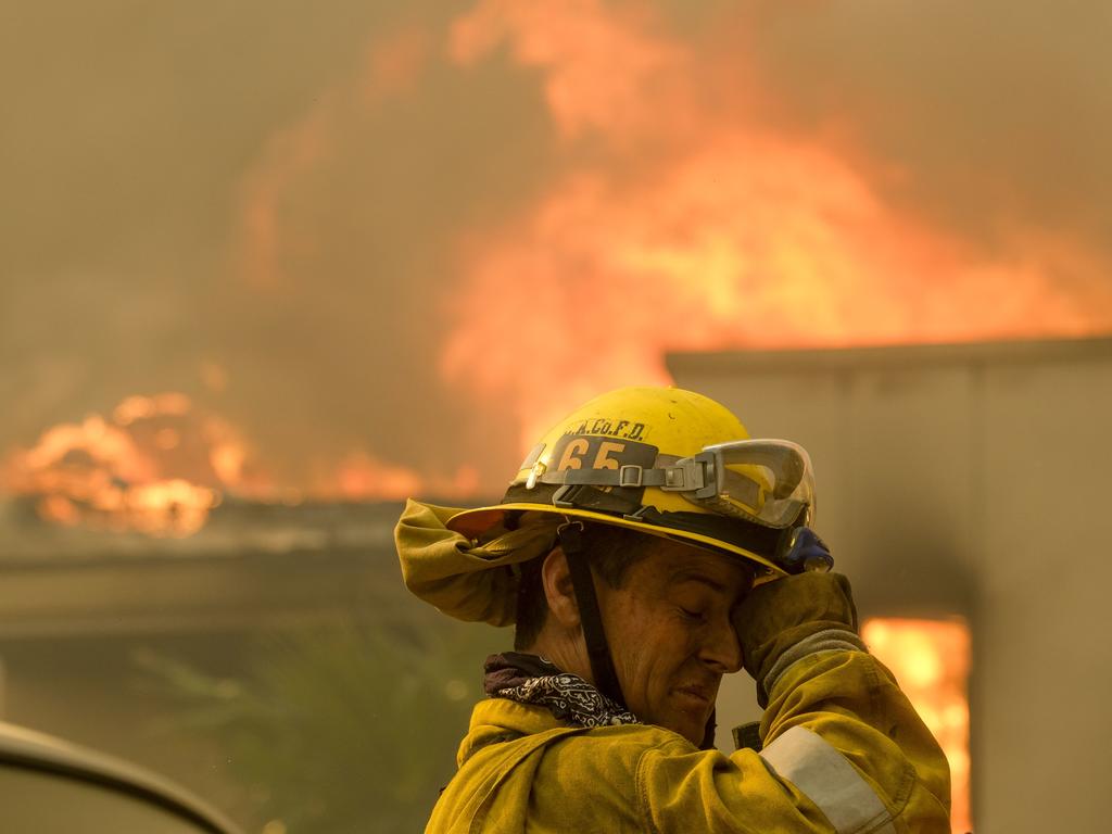 A firefighter keeps watch as the wildfire burns a home near Malibu Lake. Picture: AP