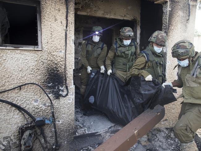 Israeli soldiers remove the body of civilian, who was killed days earlier in an attack by Palestinian militants on this kibbutz near the border with Gaza. Picture: Getty Images