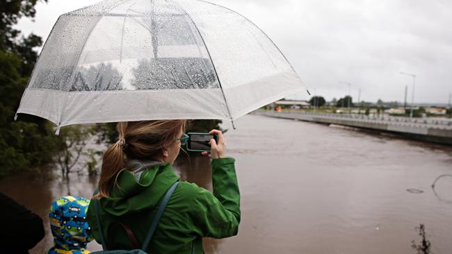 While some locals made a break for it, others were transfixed by the sight of the raging waters slamming into the bridge. Picture: Adam Yip