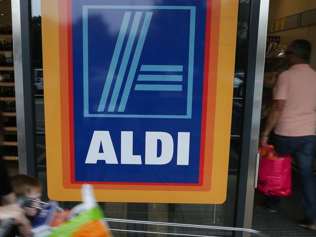 A woman pushes a shoping trolley past an Aldi logo as she leaves one of the company's supermarket stores in London on September 26, 2016. Aldi UK announced on Monday that it will invest £300 million ($389 million, 346 million euros) to revamp its stores over the next three years. Aldi and its German rival Lidl have boomed in Britain, grabbing market share from traditional supermarkets Asda, Morrison, Sainsbury's and Tesco, as customers tightened their belts to save cash. / AFP PHOTO / Daniel Leal-Olivas