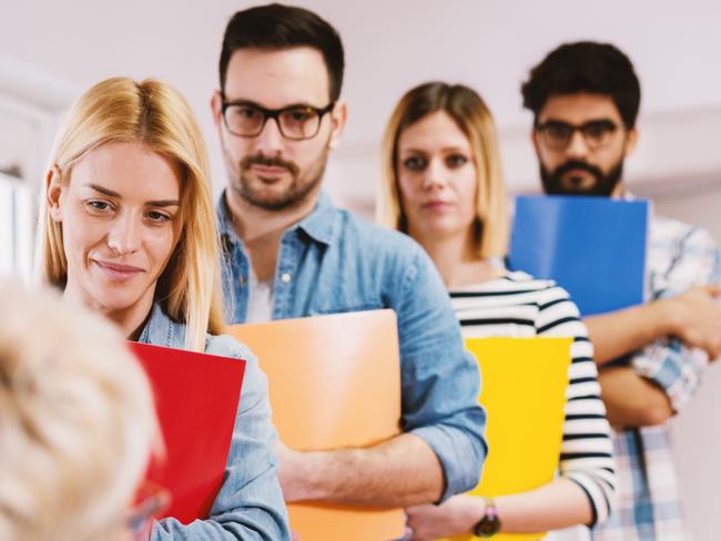 CAREERS: Group of young motivated people waiting in the line with a portfolio for a job interview.